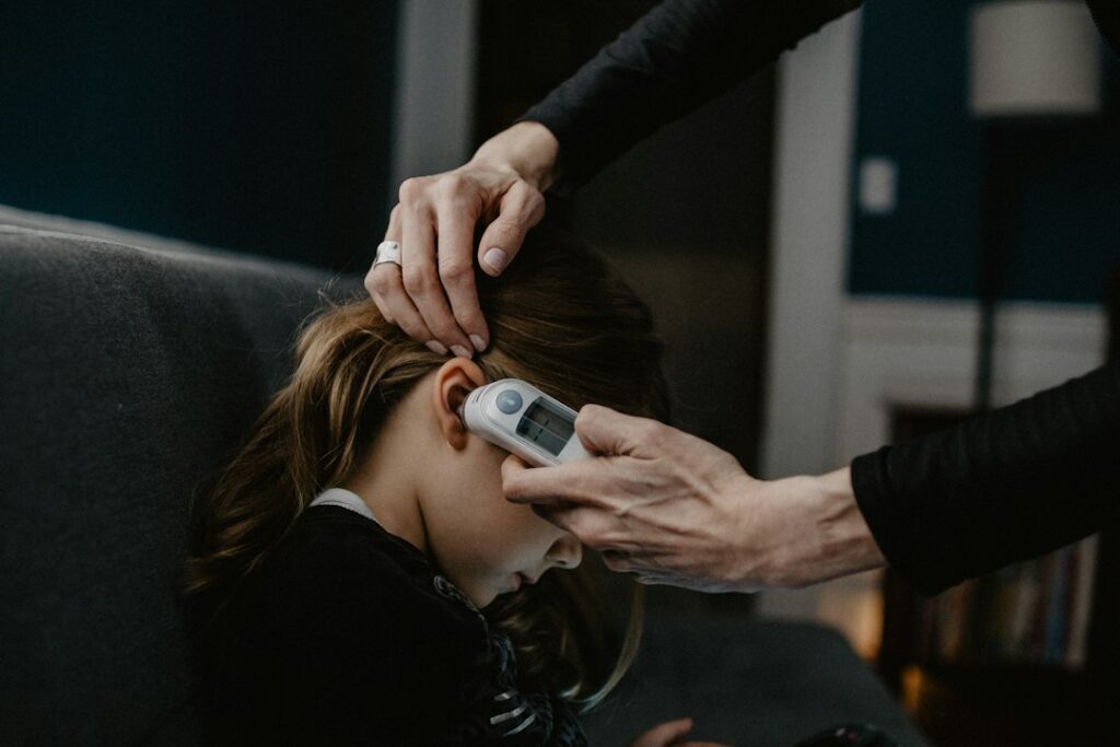 Parent checks a child’s forehead with a digital thermometer in a cool, well-lit home.