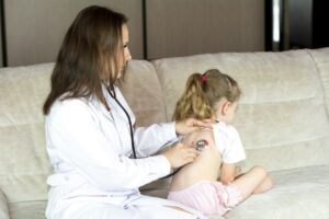Parent checks a tired child’s breathing and hydration at home while holding a thermometer.